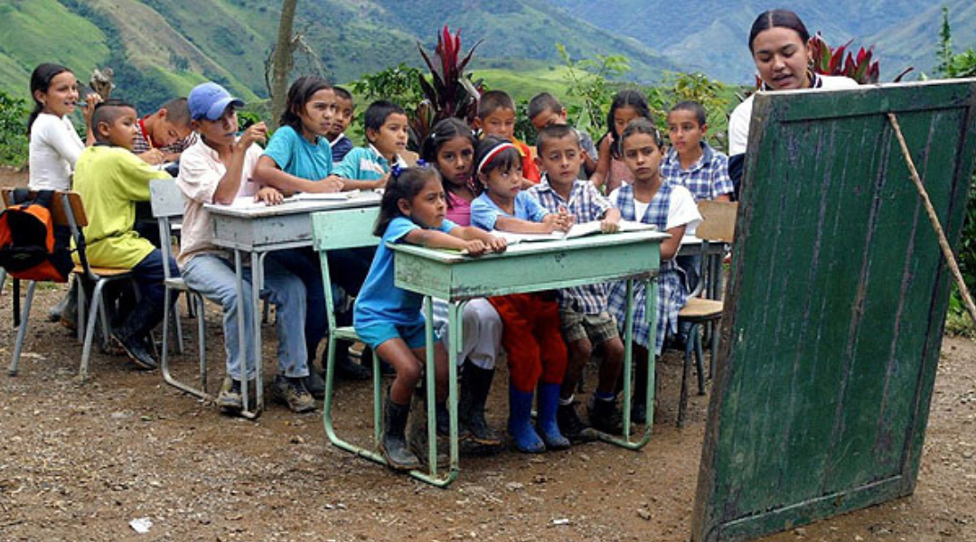 Maestro rural con estudiantes de distintos grados; fotografía de una escuela comunitaria en zona de conflicto en Colombia Maestro rural con estudiantes de distintos grados; fotografía de una escuela comunitaria en zona de conflicto en Colombia