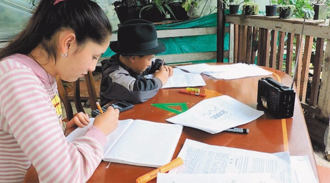 Fotografía de un niño y joven estudiando con un radio en zona rural durante la pandemia Fotografía de un niño y joven estudiando con un radio en zona rural durante la pandemia